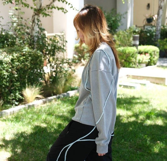 Side view of a model wearing ScervGear’s gray Swervy Sweatshirt with light-blue curved seam accents.