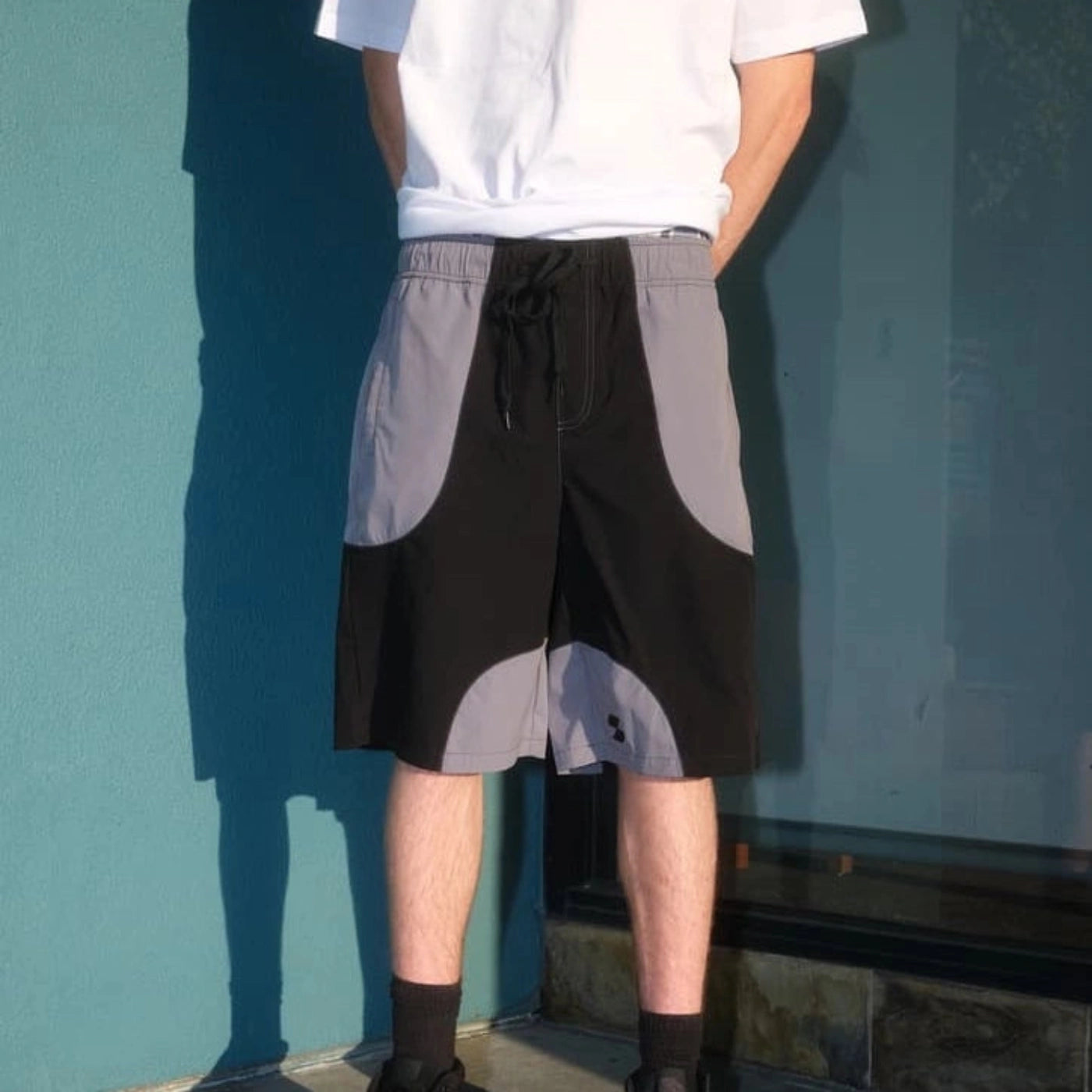 Model wearing black and gray Scerfer Baggy Boardshorts with adjustable drawstring waistband and relaxed active streetwear fit.