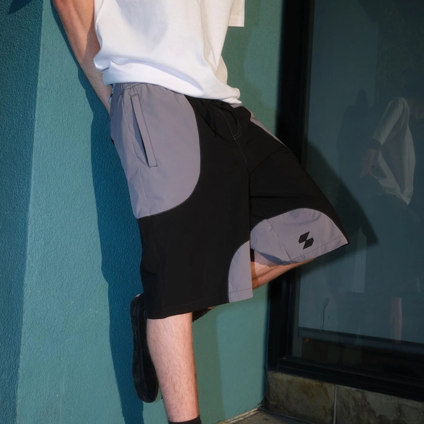 Model wearing black and gray Scerfer Baggy Boardshorts with adjustable waistband and relaxed active streetwear fit.