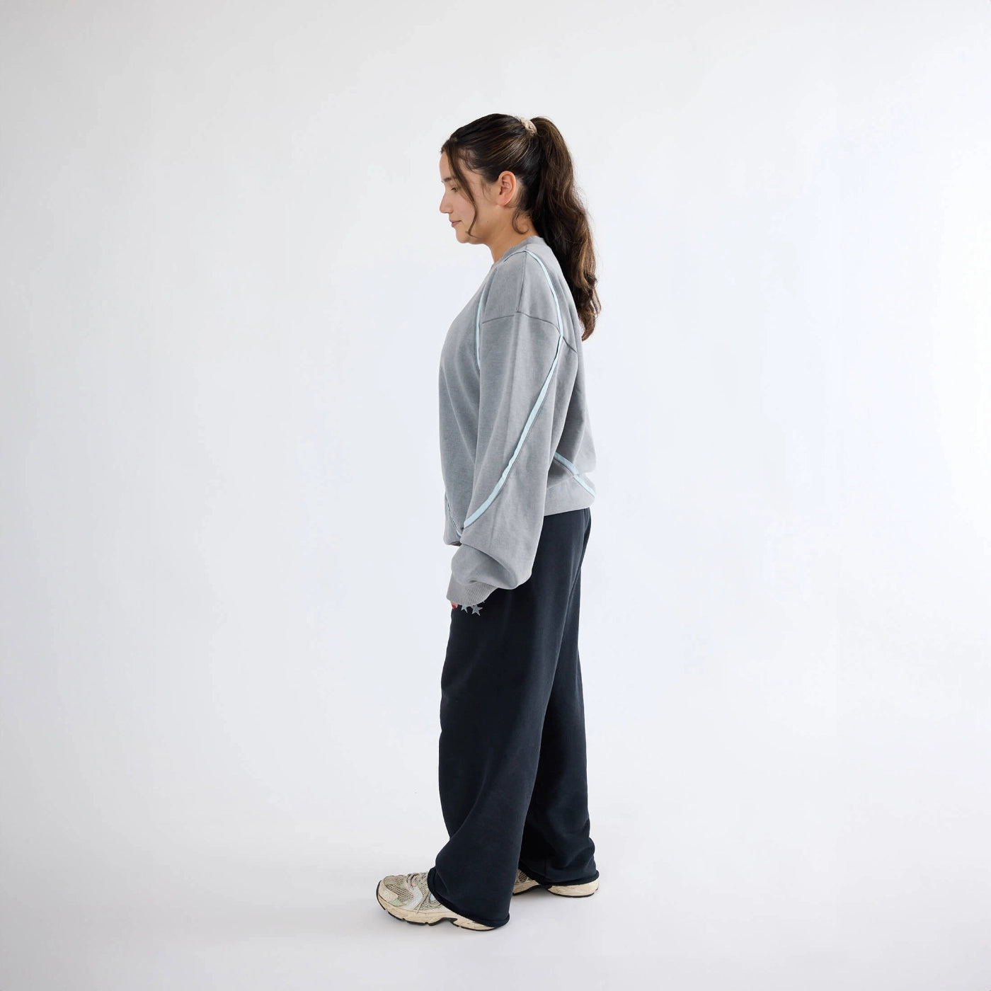 Side view of gray Swervy Crewneck sweatshirt with relaxed fit and curved seam detailing for active streetwear.