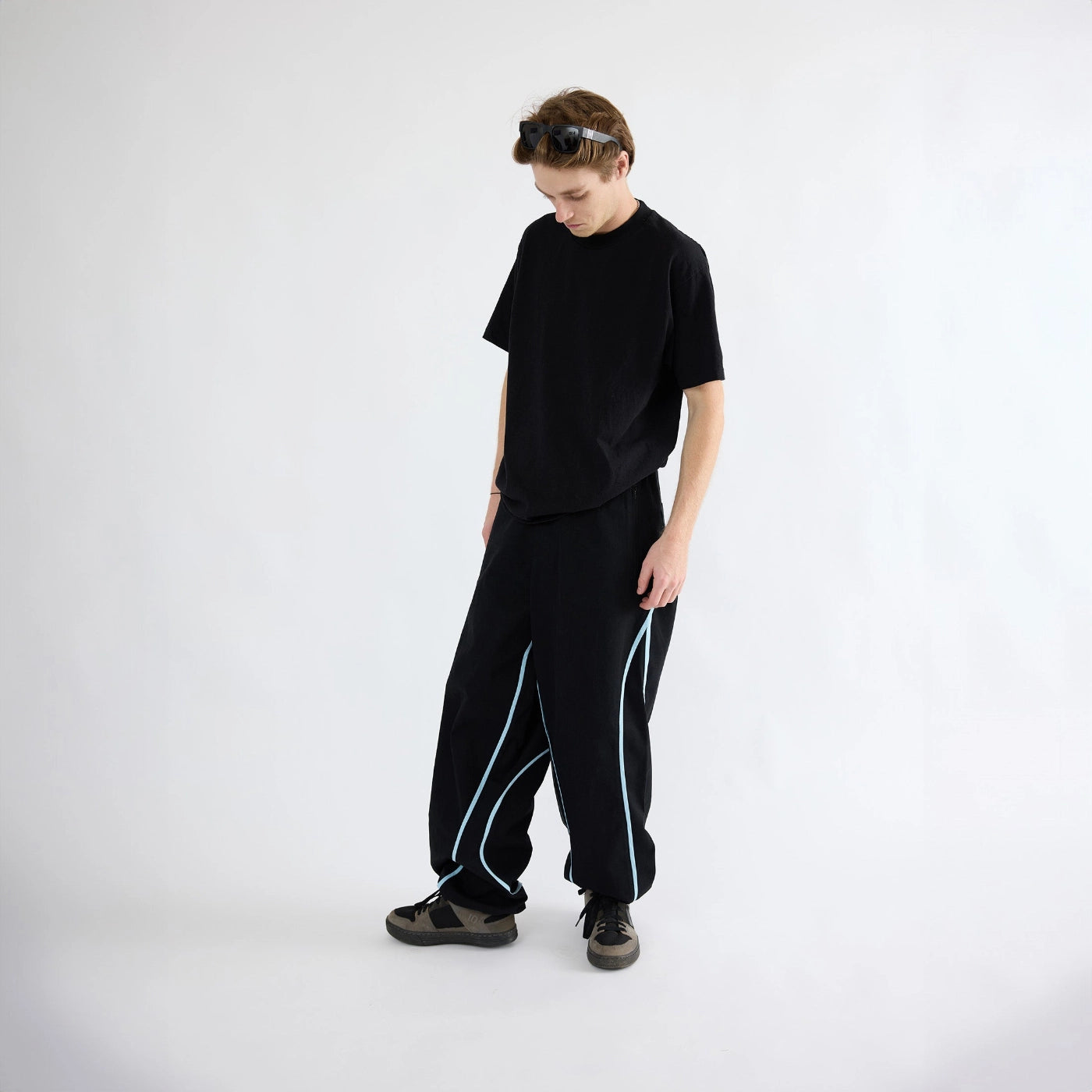 Model wearing black Curvy Baggy Pants with curved seam detailing, built-in belt waistband, and relaxed motion-first fit for active streetwear.