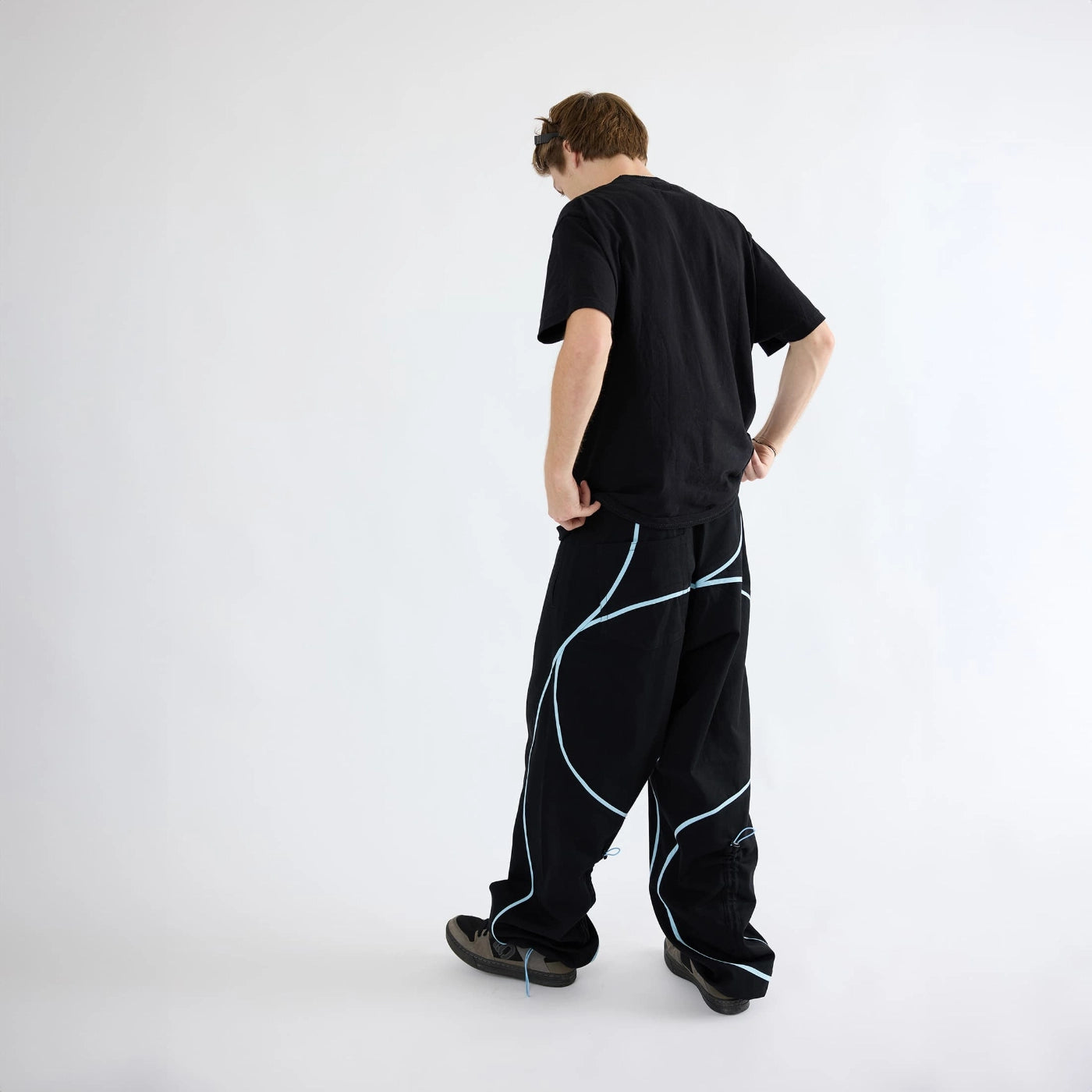 Angled back view of black Curvy Baggy Pants showing curved seam design and relaxed active streetwear fit.